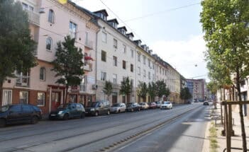 Streetview of light colored houses with trees and cars
