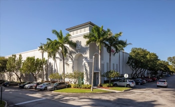 Front side of white office building surrounded by palm trees