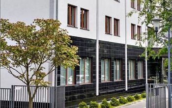 Front side of black and with office building surrounded by greenery