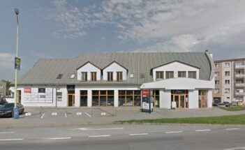 Street view of frontside of white office building and grey roof