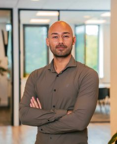 Man in brown shirt smiling at the camera