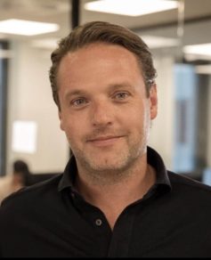 Man in black shirt smiling at camera
