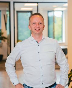 Man in white blouse in office smiling at the camera