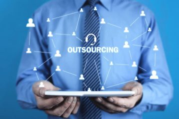 Outsourcing-call-center-qmsfr92k6byo516bgmrohlfocepd196xte2at3o1cu Man in blue suit holding a tablet displaying a network of people with in the middle the word Outsourcing