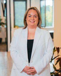 Woman in white blazer smiling at the camera