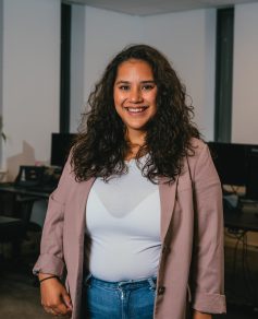 Woman with dark hair smiling in thee camera