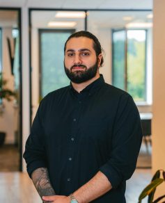 Man with black shirt in office smiling at camera
